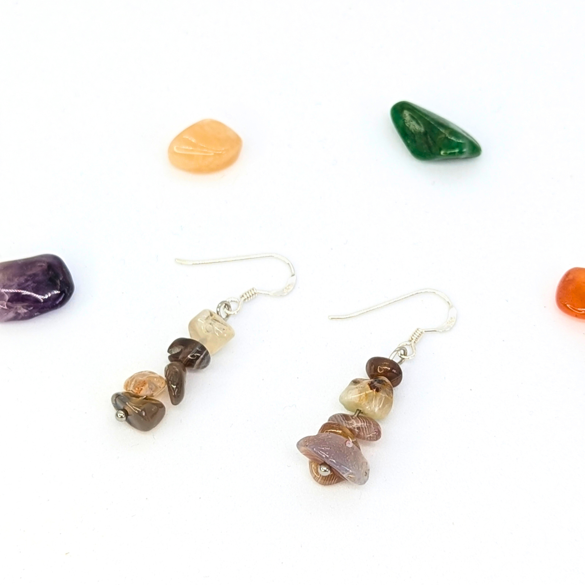Silver Sunbird’s Botswana Agate Gemstone Earrings feature handmade stacked agate beads in neutral tones, displayed on a white background with vibrant orange, green, purple, and red polished stones.