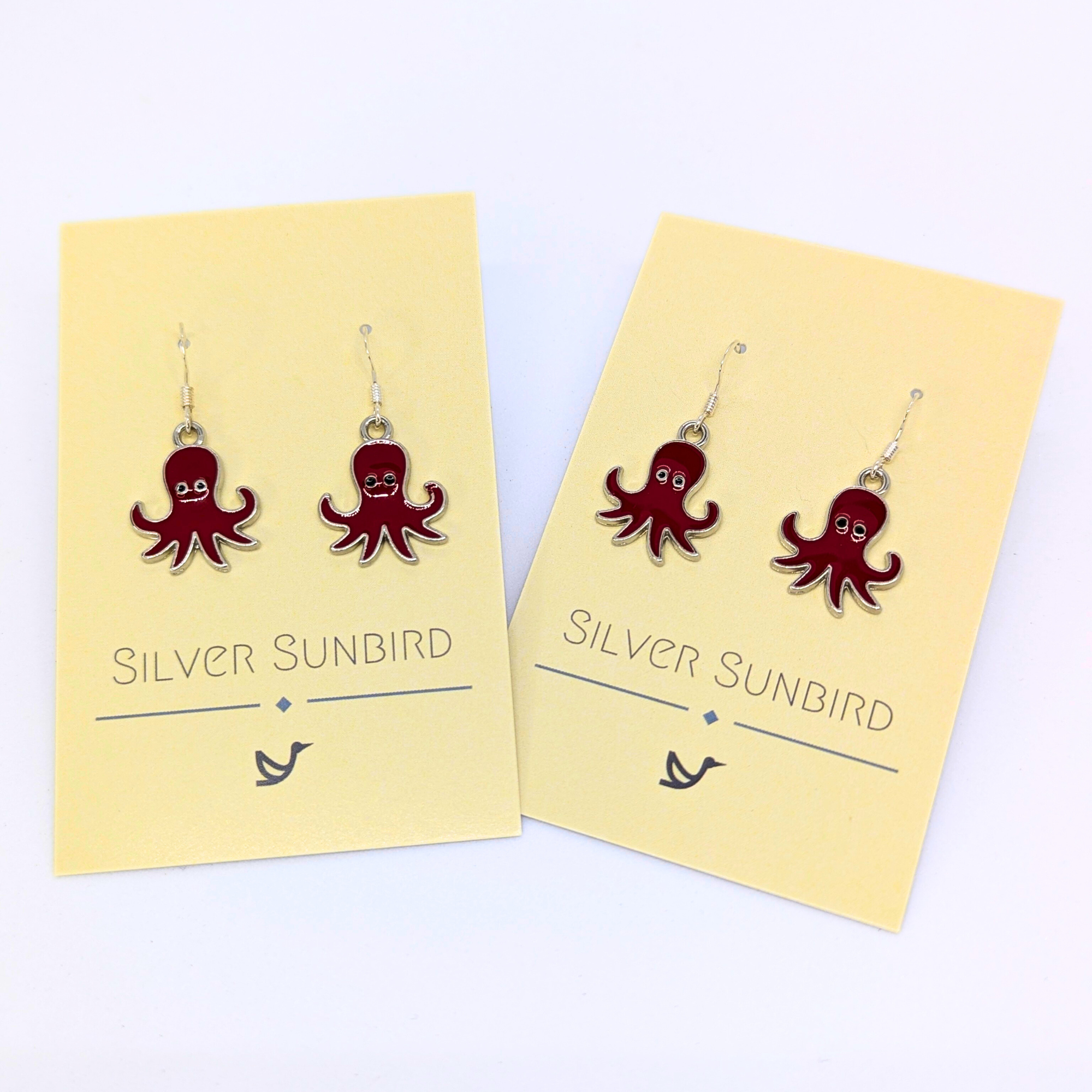 Two pairs of Red Octopus Earrings by Silver Sunbird, displayed on cream cards. These ocean-inspired earrings feature a playful smiling octopus design, perfect for adding charm to any jewelry collection.