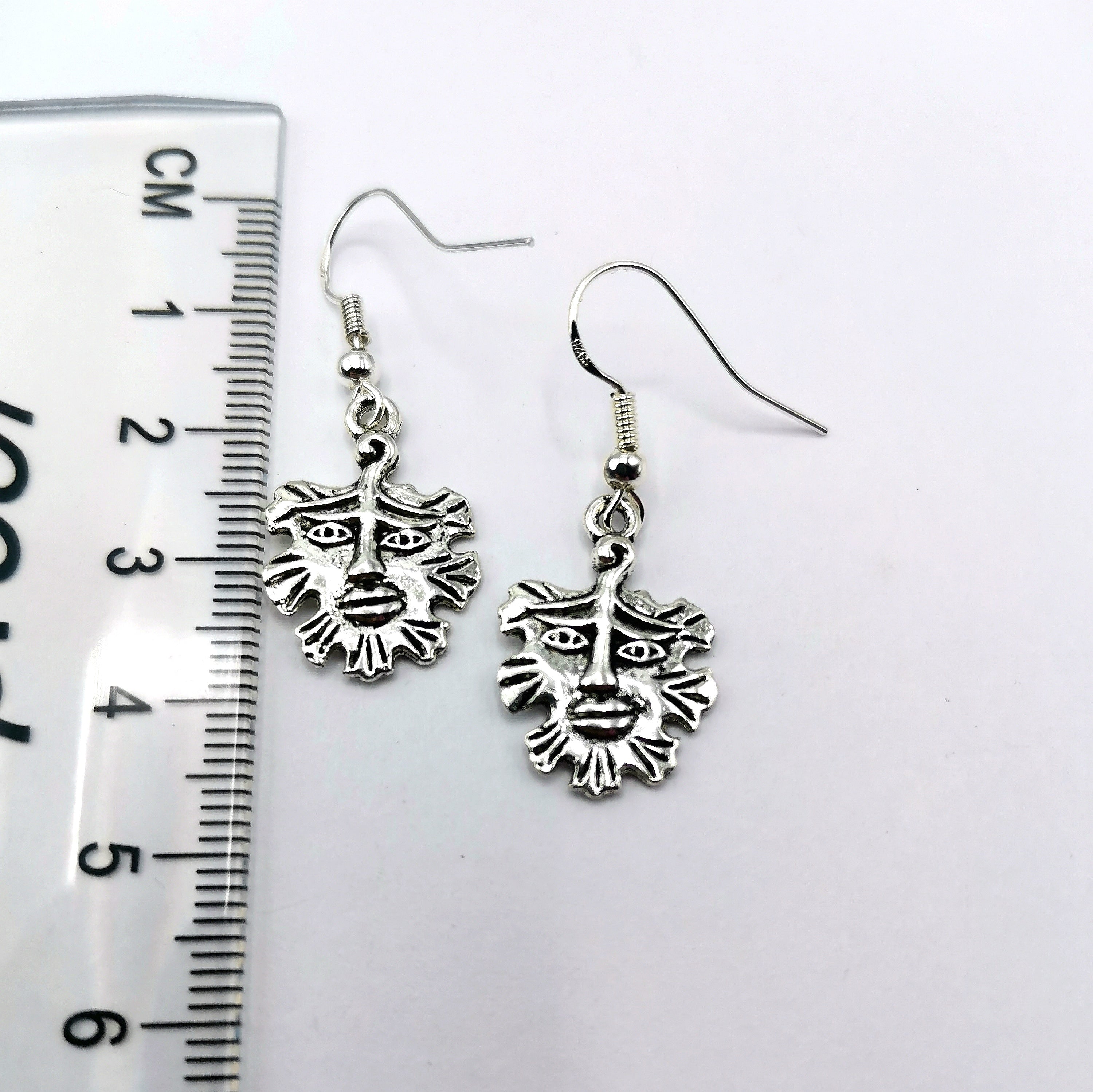 The Gentle Green Man Sterling Silver Earrings by Silver Sunbird, each about 3 cm long with detailed face designs, are shown beside a ruler against a white background—unique pagan-inspired jewellery.