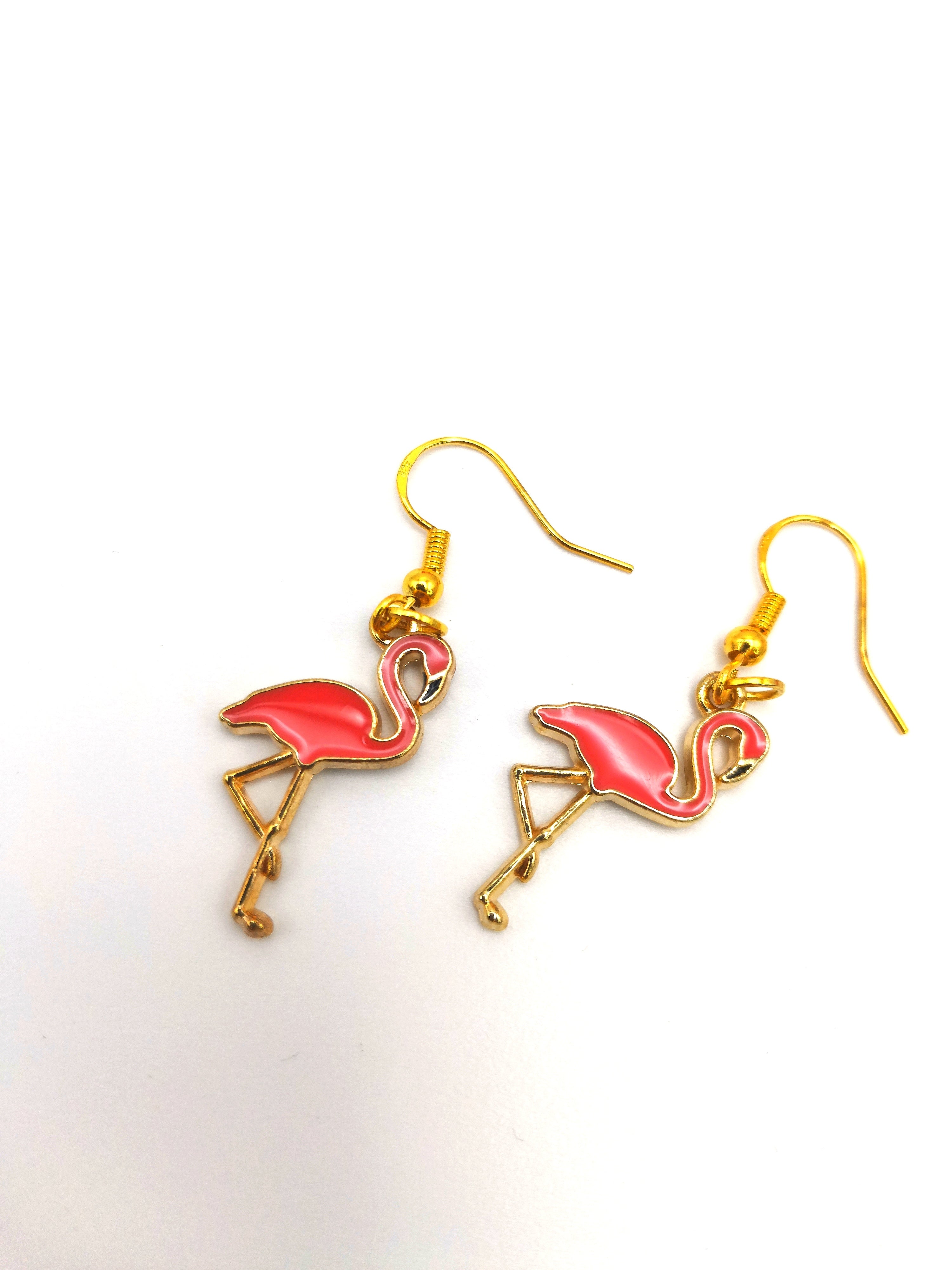 Introducing the Dancing Flamingo Earrings by Silver Sunbird, featuring handcrafted enamel pink flamingo charms with their legs crossed in a classic stand pose. These enchanting earrings boast gold-plated hooks and are outlined in gold, made from gold-plated sterling silver. Set against a plain white background, each piece is a charming addition to any collection.