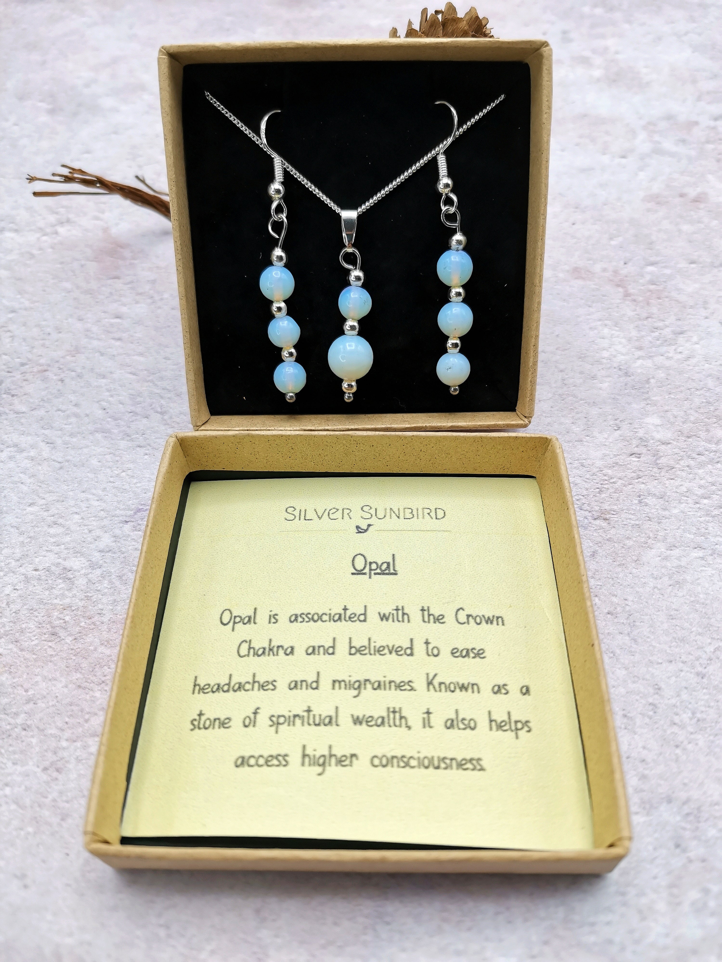 The Silver Sunbird Opal Gemstone Gift Set, a sterling silver necklace and earrings set, is elegantly presented in a jewelry box. An included card highlights the opal&