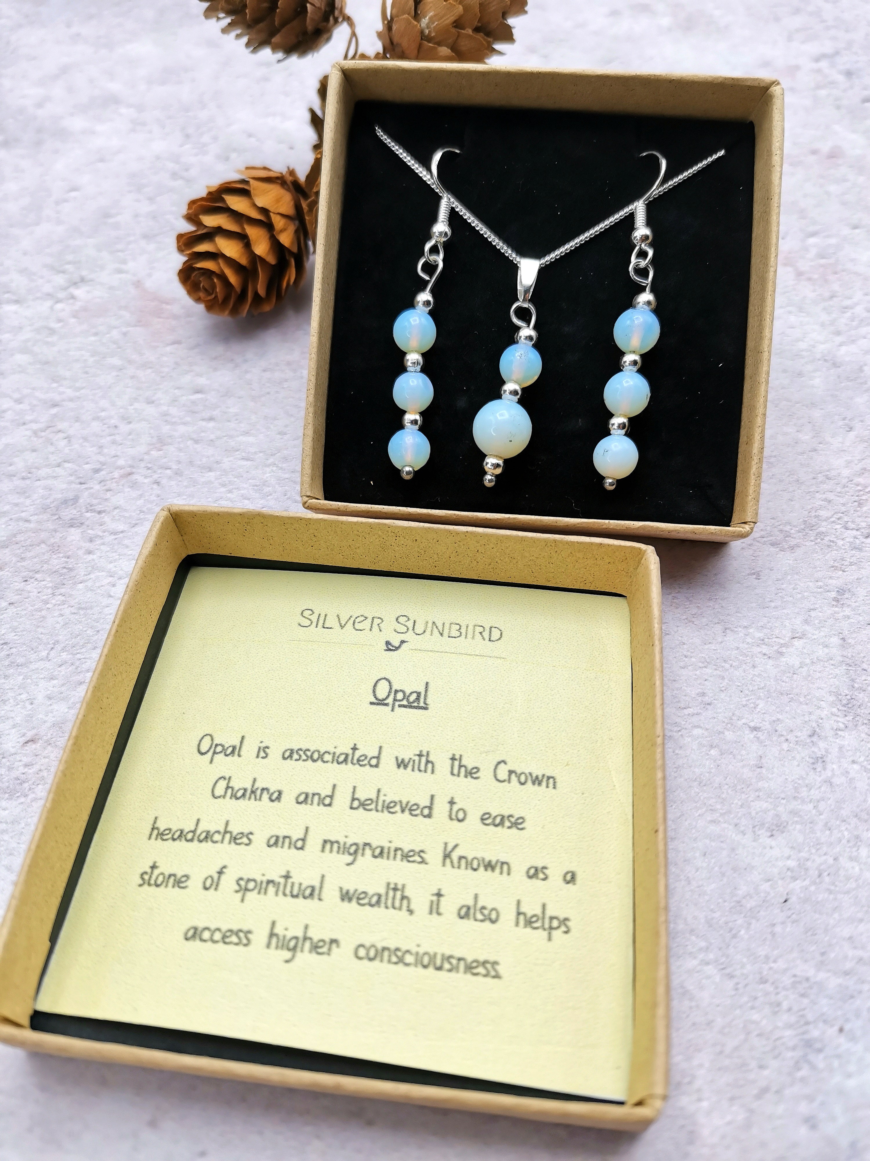 The Opal Gemstone Gift Set by Silver Sunbird includes opal earrings and a matching necklace with sterling silver accents in an open box, accompanied by a card describing opal&