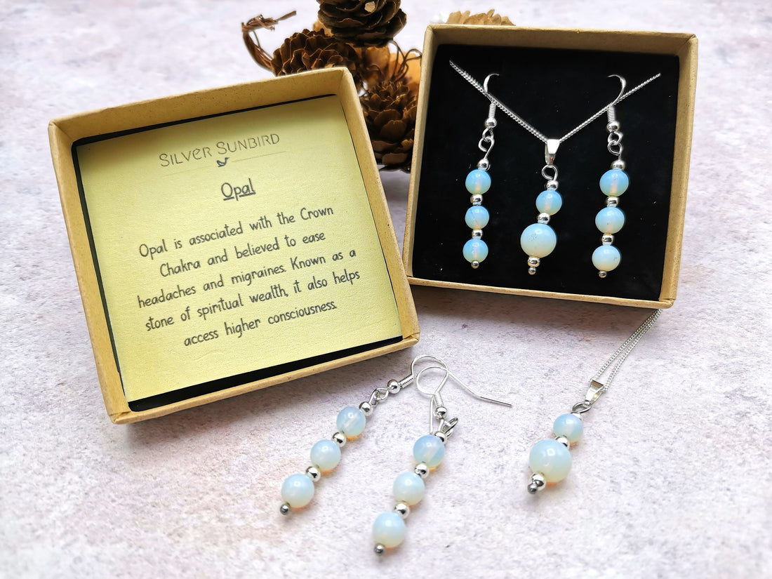 The Silver Sunbird Opal Gemstone Gift Set includes opal earrings and a necklace, finely crafted in sterling silver, presented in a decorative box. It notes the opal&