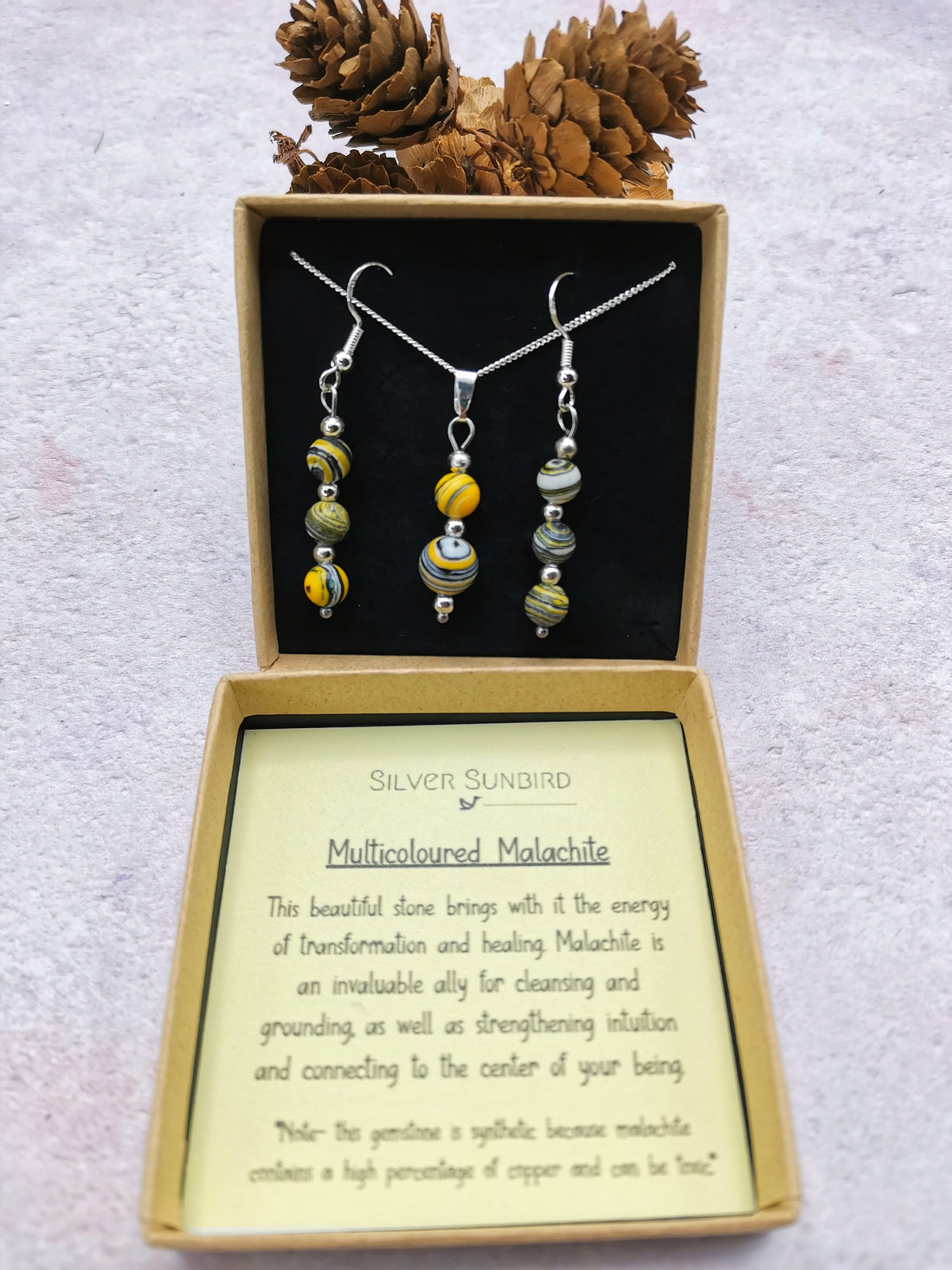 The Silver Sunbird Multi-coloured Malachite Gemstone Gift Set includes a sterling silver pendant necklace and bead earrings, displayed in an open box with a card about malachite&