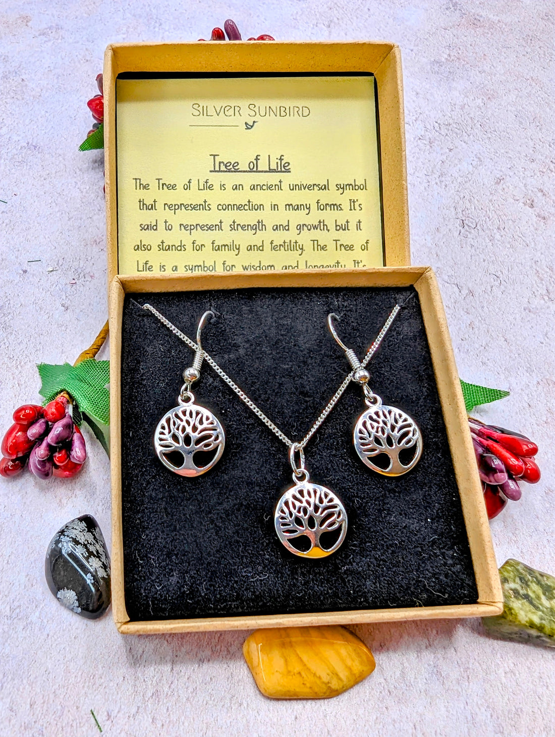 The Sterling Silver Tree of Life Jewellery Set – Necklace & Earrings by Silver Sunbird features a pendant necklace and hypoallergenic earrings with a Tree of Life motif, elegantly boxed with symbolism card and decorative stones.