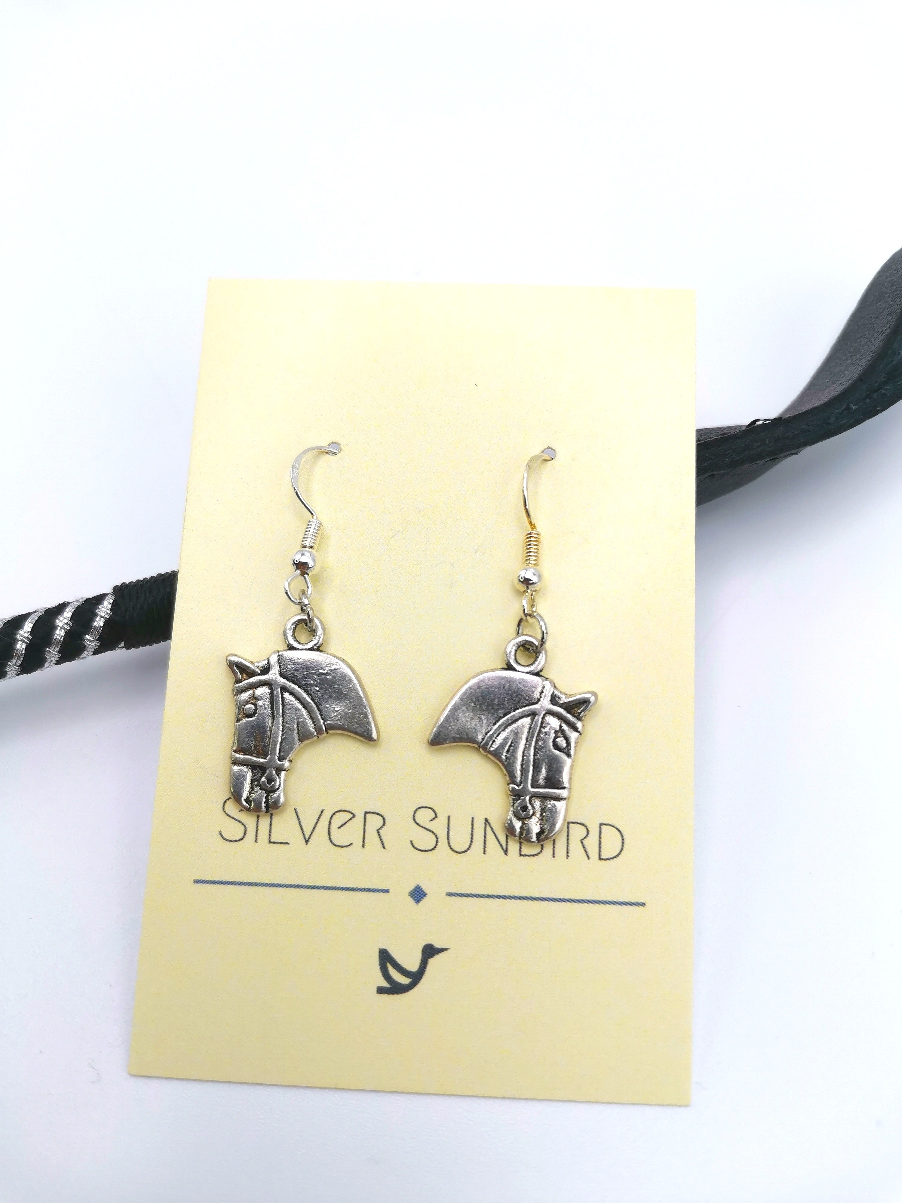 Beautifully showcased on a yellow card with the label "Silver Sunbird," the exquisite Take The Reins Equine Earrings make the ideal equestrian jewelry piece for any horse enthusiast&