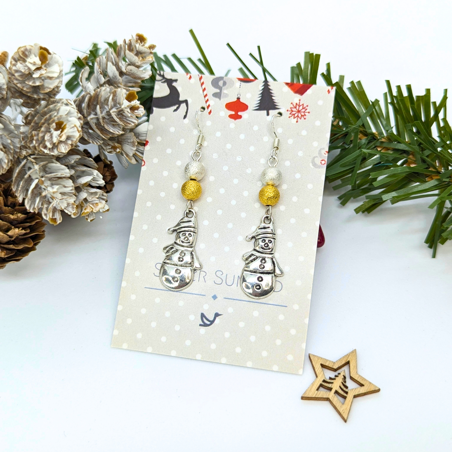 Add holiday cheer with the Very Merry Snowmen Earrings by Silver Sunbird—handmade sterling silver earrings with gold beads, displayed on a festive card and perfect for gifting or wearing this season.