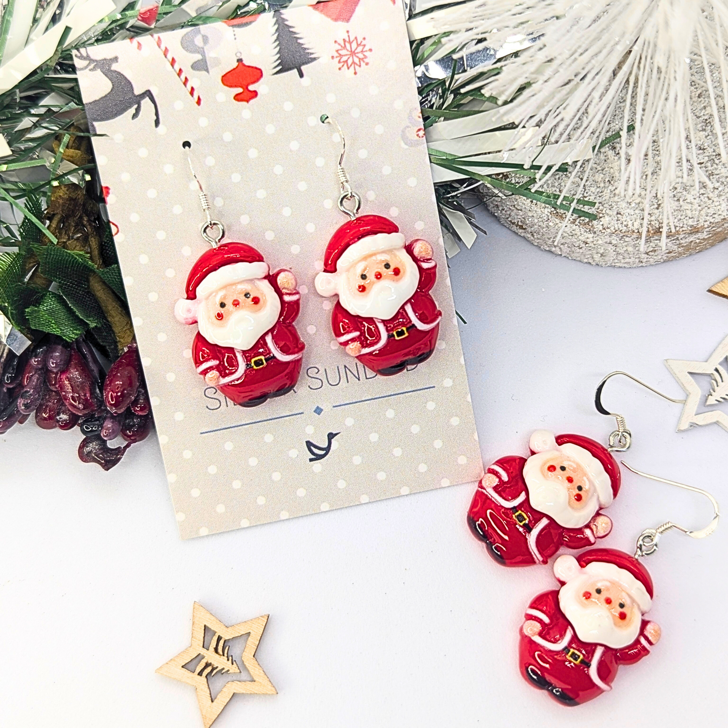The Jolly Santa Earrings by Silver Sunbird come on a festive polka dot card adorned with cheerful decorations such as pine branches and stars, making them the perfect Christmas accessories to add a touch of holiday spirit.