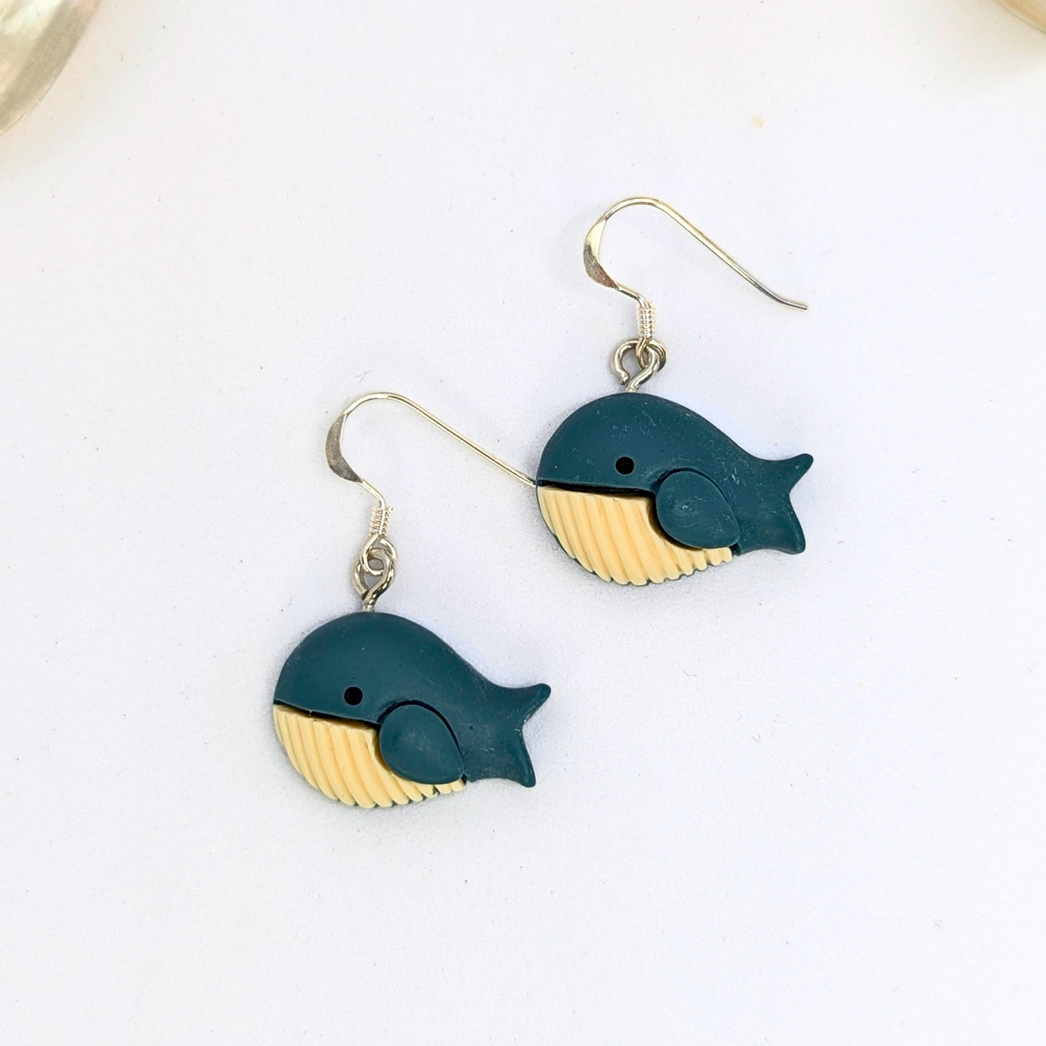 Colourful Whale Earrings by Silver Sunbird feature nautical whale shapes with dark blue bodies and beige undersides, shown on a white background.
