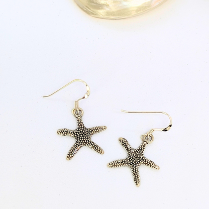 Silver Sunbird’s Detailed Silver Starfish Earrings feature a textured design, perfect for boho jewelry lovers. These sterling silver earrings dangle elegantly and are shown on a white background.