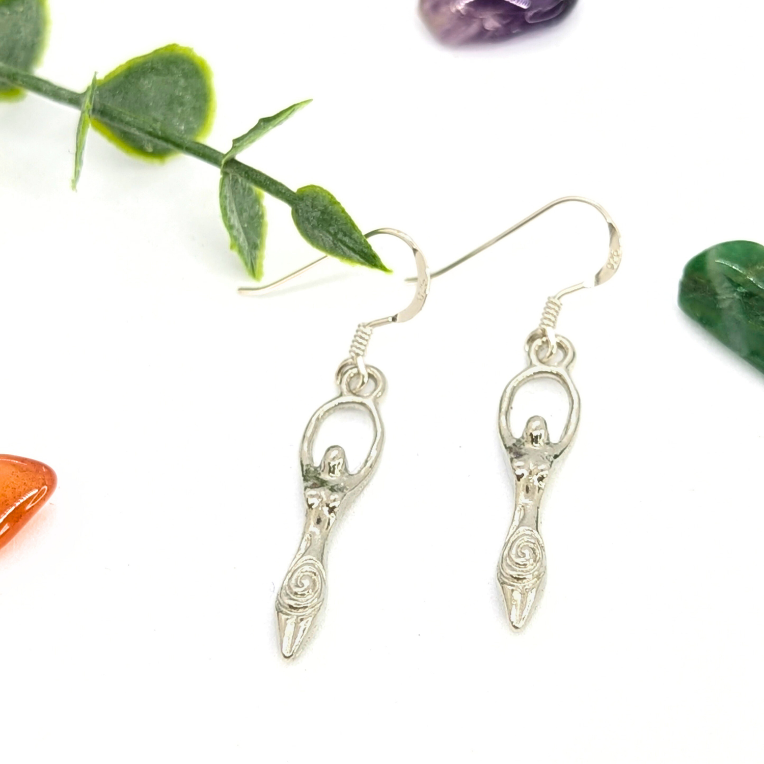Handmade Fertility Goddess Dangle Earrings by Silver Sunbird, featuring spiral details. Displayed on white with green leaves and colorful stones—perfect boho earrings for a distinctive, goddess-inspired style.