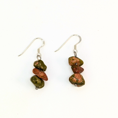 The Silver Sunbird Unakite Gemstone Earrings are handmade dangle earrings with silver hooks, each showcasing three stacked green and reddish-brown Unakite beads. This crystal jewelry is displayed on a white background.