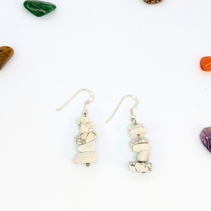 Silver Sunbird’s White Howlite Gemstone Earrings, featuring stacked marbled stones, are displayed on a white surface with colorful tumbled stones—an ideal choice for handmade jewellery enthusiasts.