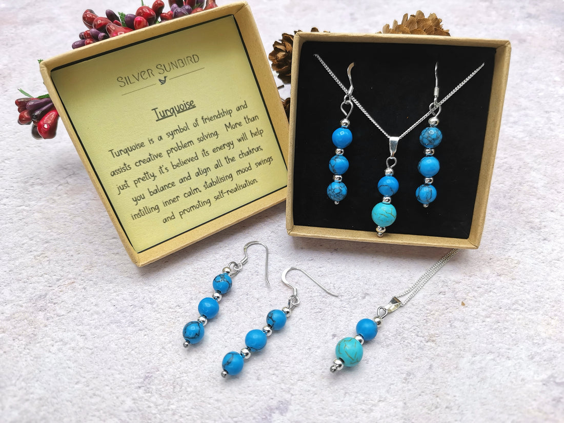 The Silver Sunbird Turquoise Gemstone Jewellery Set – Sterling Silver Necklace & Earrings is shown beside a box and card highlighting turquoise as a symbol of friendship and protection.